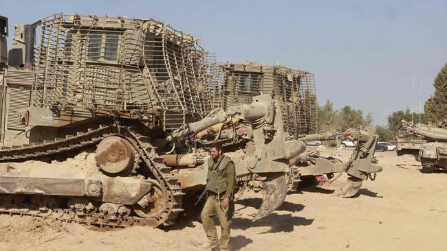 An Israeli soldier walks past army bulldozers deployed near the border with Gaza. Picture: Menahem Kahana/AFP