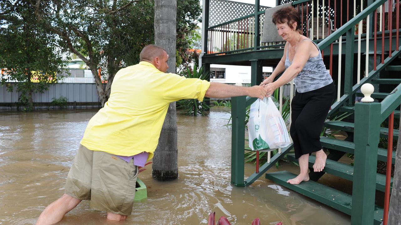 Keith Scanlan gets hot water for a coffee to June Rowles at home in George St after she lost power in the 2010/11 floods. Photo: Paul Beutel