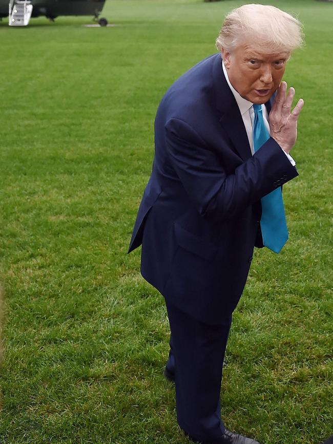 US President Donald Trump whispers to a White House staffer on the South Lawn of the White House. Picture: AFP