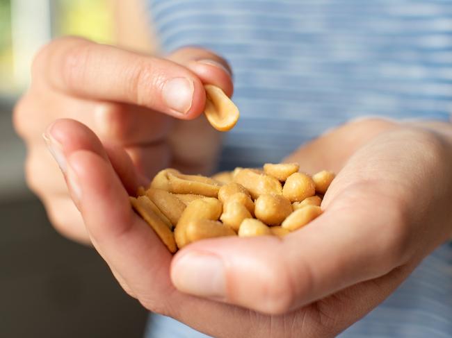 Close Up Of Teenage Girl Eating Handful Of Salted Peanuts. Picture: Getty Images