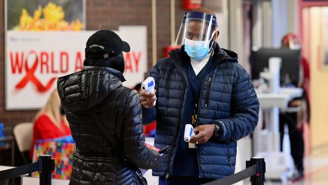 A staff member checks the temperature of a visitor at Woodhull Medical and Mental Health Center in New York. Picture; AFP.