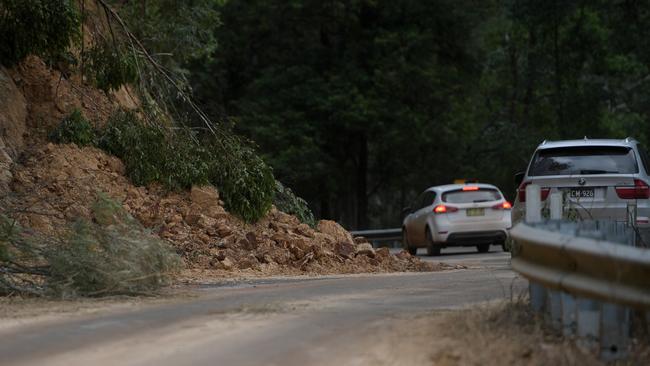 Cars drive past landslides on the Kyogle Rd near Uki, New South Wales. (AAP Image/Tracey Nearmy).