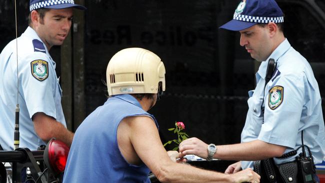 A woman hands a rose to a police officer at the scene of the murder of store owner Frank Newbery, 87, in Union Street, Newcastle.