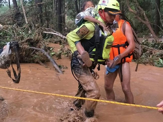 This handout photo from the Thai Rescue Team shows a member carrying a young flood survivor close to the swollen river in Attapeu province. Picture: AFP