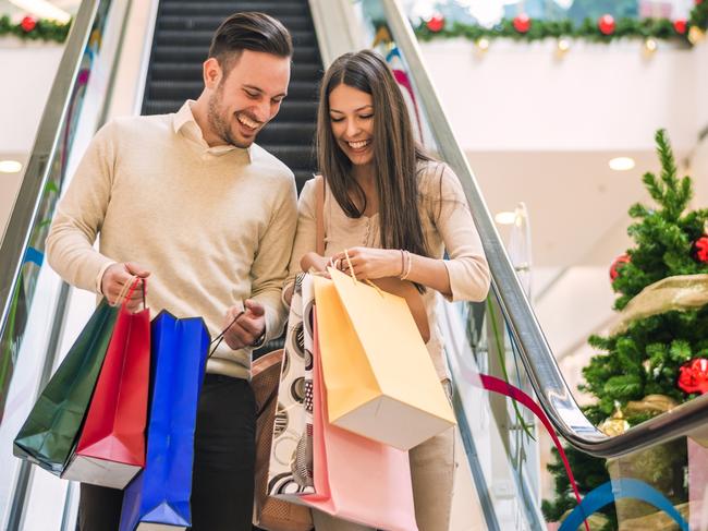 Romantic Christmas shopping.Sale, technology and people concept - happy young couple with shopping bags.Image taken inside a shopping mall.