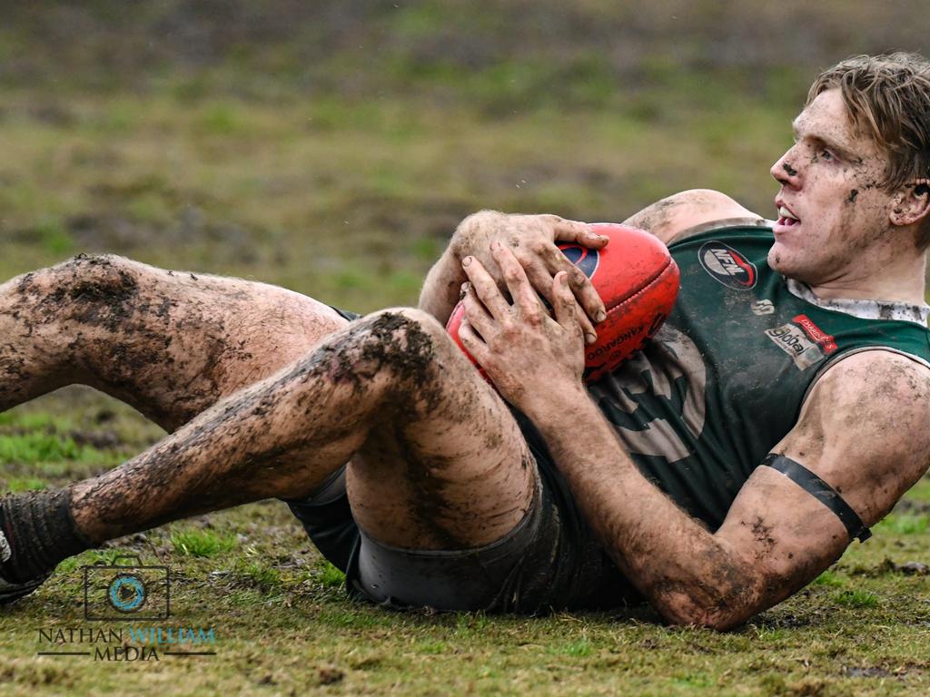 Greensborough’s Tom Bell slides through the mud to mark. Pictures: Nathan McNeill.