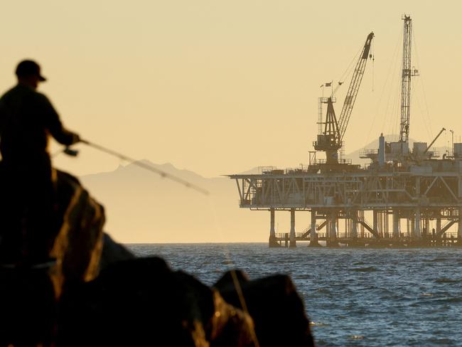 SEAL BEACH, CALIFORNIA - JANUARY 05: A person fishes with offshore oil and gas platform Esther in the distance on January 5, 2025 in Seal Beach, California. President Joe Biden will reportedly permanently ban future offshore oil and gas drilling in over 625 million acres of federal waters in an effort to cement his environmental legacy before President-elect Donald Trump is inaugurated January 20th. Platform Esther is located approximately 1.5 miles away from Seal Beach and operates within California state waters.   Mario Tama/Getty Images/AFP (Photo by MARIO TAMA / GETTY IMAGES NORTH AMERICA / Getty Images via AFP)