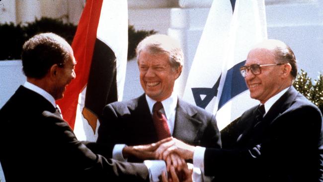 Egyptian President Anwar Sadat, left, US President Jimmy Carter and Israeli Prime Minister Menachem Begin clasp hands on the lawn of the White House as they complete signing of the peace treaty between Egypt and Israel.