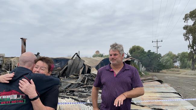 Owner of the Ky West Hotel Matt Ford is embraced by pub patron Liz Young, at the scene of the beloved pub. It was burned to the ground on March 21. Behind them is former owner of the hotel, Wayne Cowley. Picture: Julieanne Strachan