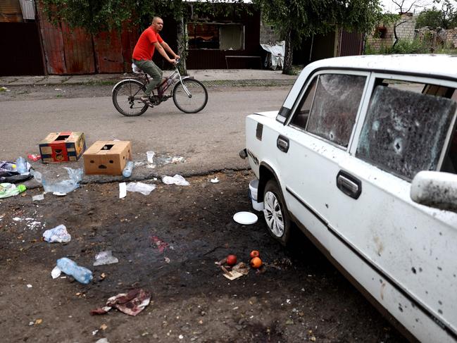 A man rides past a place where a woman was killed by a Uragan cluster missile strike in Lyman. Picture: AFP