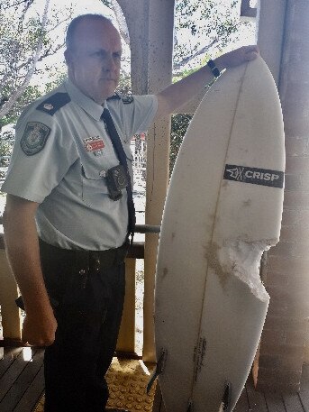 Matt Kehoe the Detective Inspector and Officer in Charge at Byron Bay Police Station with the surfboard of the shark attack victim. 