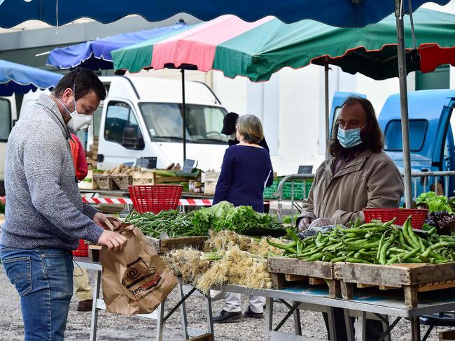 A vendor wearing a protective face mask watches a customer choosing vegetables at the open Cadillac market near the southwestern city of Bordeaux. Picture: AFP