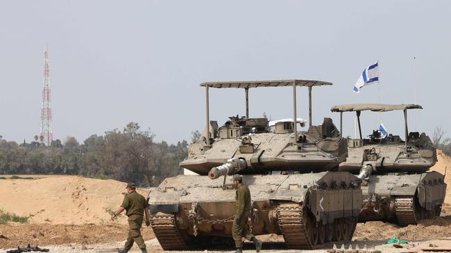 Israeli army soldiers walk past tanks at a position near Israel's southern border with the Gaza Strip on March 6. Picture: AFP