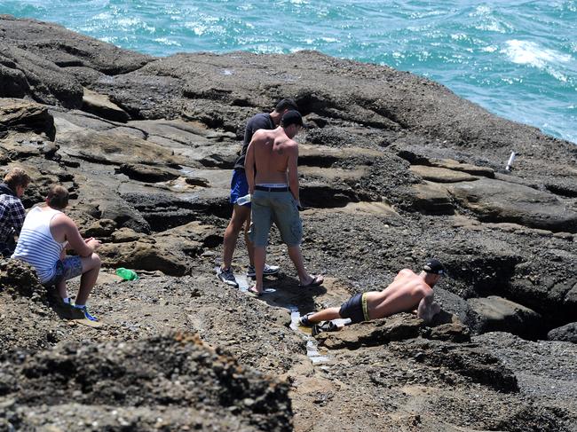 Friends and relatives revisit the spot at Snapper Point where rock fisherman Jesse Howes was washed into the ocean and is missing, presumed drowned. Picture: Peter Lorimer