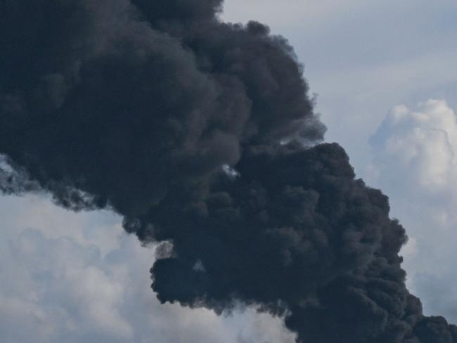 Black smoke from an oil tank on fire is seen in Matanzas, Cuba, on August 6, 2022. - Planes with products, firefighters and specialists from Mexico and Venezuela arrived in Cuba to help put out this Sunday the fire of two oil tanks, which enters its third day with one dead, 17 missing and 36 hospitalized. (Photo by YAMIL LAGE / AFP)