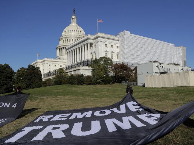 Demonstrators place large banners on the lawn adjacent to the US Capitol during the first public impeachment hearings of Donald Trump. Picture: AP Photo/Julio Cortez