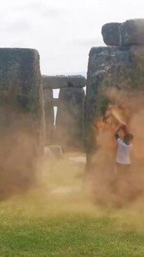 Onlookers try to drag away activists blasting paint on Stonehenge