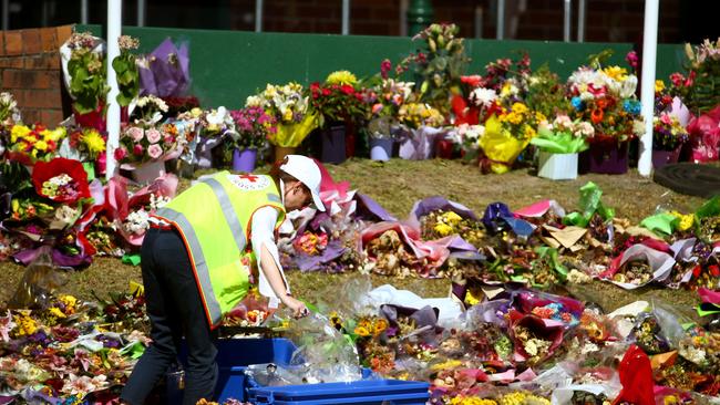 Red Cross volunteers start to remove flowers from Dreamworld yesterday. The tributes will form part of a living memorial. Picture: David Clark