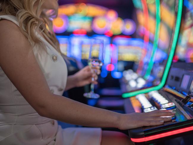 beautiful girl drinking wine alone at casino poker machine pokies istock generic