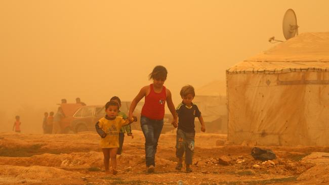 Syrian children caught in a sandstorm on Monday at a refugee camp in Lebanon, one of five primary host nations for Syrian refugees. Picture: AFP / STR