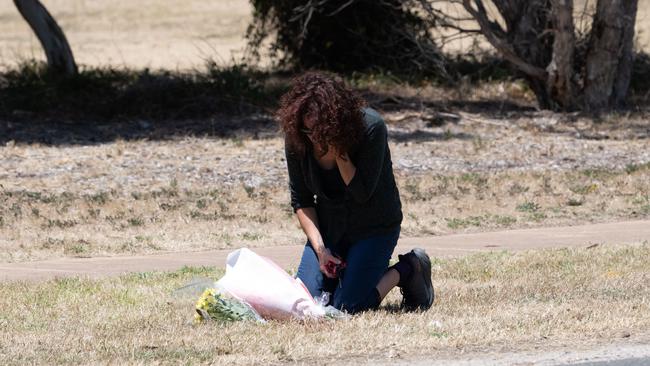 A woman lays flowers at the spot where Charlie Stevens was struck by a car on Friday night. (The Advertiser/ Morgan Sette)