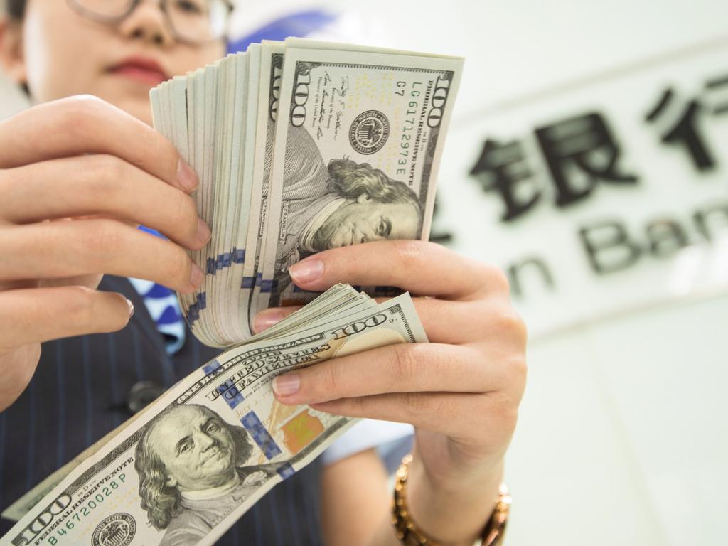 A Chinese bank employee counts US dollar bills at a bank counter in Nantong in China’s eastern Jiangsu province Picture: STR/AFP