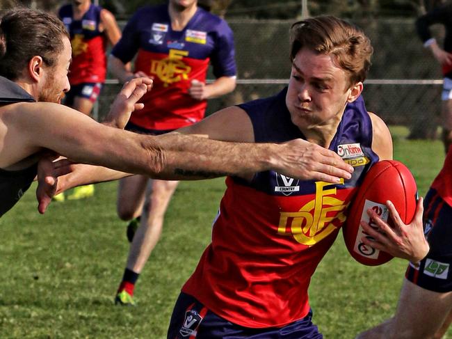 RDFL footy: Riddell v Diggers Rest. Deven Costigan Diggers Rest handballs under pressure from Gavin Urquhart Riddell. Picture: Aaron Cook