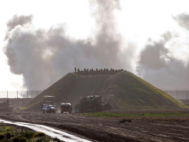 This picture taken from a position in southern Israel near the border with the Gaza Strip shows smoke billowing following Israeli bombardment as troops gather on a hill. Picture: AFP