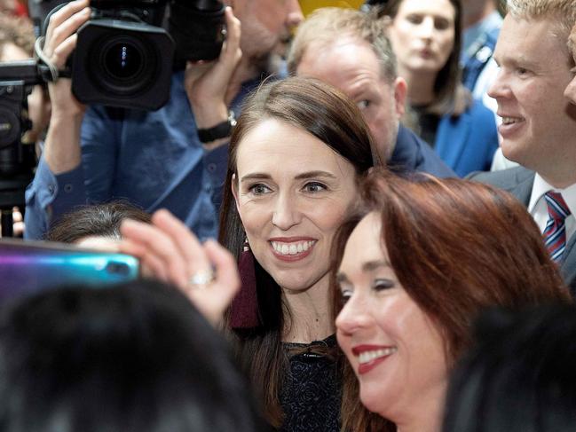 New Zealand's Prime Minister Jacinda Ardern (C) poses for photos with students while campaigning at Victoria University in Wellington on October 13, 2020, ahead of the country's general election on October 17. (Photo by Marty MELVILLE / AFP)