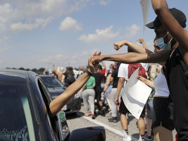 A motorist gets a fist bump from a passing protester as a demonstration shuts down a highway in St. Charles. Picture: Jeff Roberson