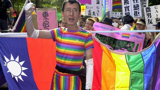 A gay activist in Taiwan carrying the national flag (left) and a rainbow flag (right). Picture: AFP.