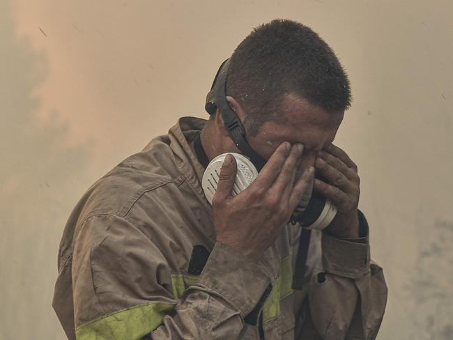 A fireman wipes his eyes as he battles flames burning vegetation during a wildfire near Prodromos, 100km northeast from Athens, on August 21, 2023. (Photo by Spyros BAKALIS / AFP)