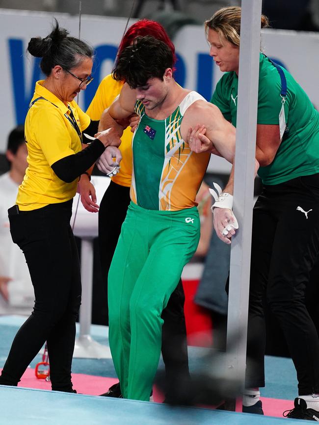 Clay Stephens is helped by officials after injuring himself performing on the rings during the 2020 World Cup of Gymnastics at Melbourne Arena on Thursday. Picture: AAP Image/Scott Barbour