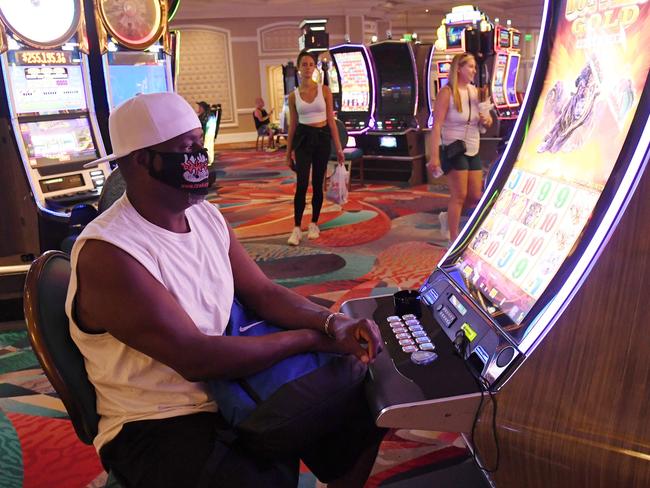 Texan Wayne Rogers wears a mask as he plays the pokies. Picture: AFP