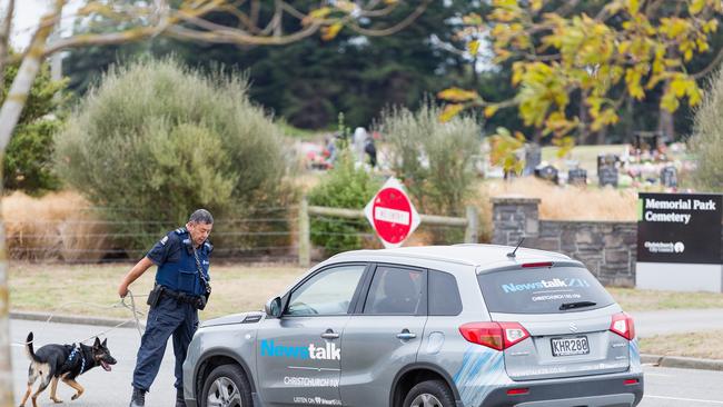 A police dog handler checks parked cars at Memorial Park Cemetery prior to the first burials of victims today. Picture: Kai Schwoerer/Getty