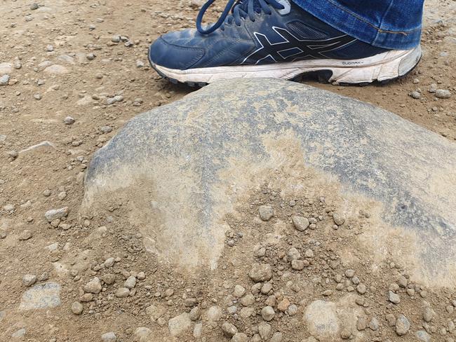 Bronte Park shop owner Shane Hedger gives an indication of how big some of the exposed rocks on Marlborough Road are, by lining up one of them next to his shoe. Picture: Supplied