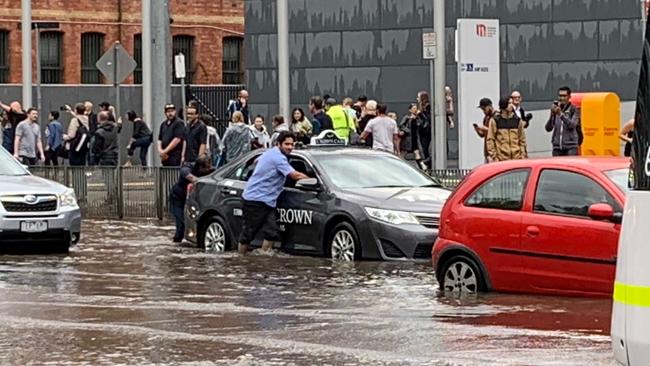 A taxi driver pushes his car through floodwater on Clarendon St in South Melbourne. Picture: Craig Hughes