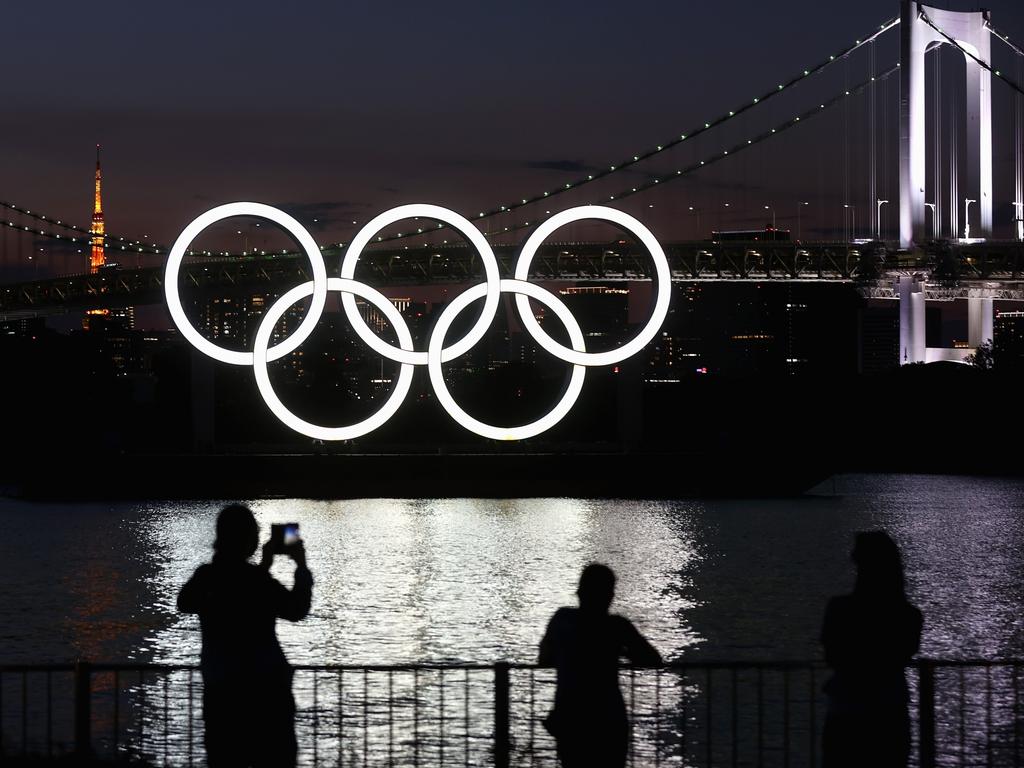 People take photographs of illuminated Olympic rings on display for the Tokyo 2020 Olympic Games. Picture: Alexander Hassenstein/Getty Images