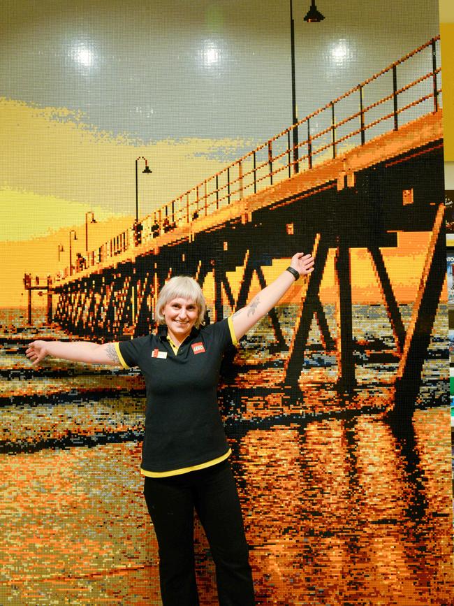 Store manager Maria Trouptsidis in front of a large mosaic of Glenelg jetty, at the official lego store on level 2 of Westfield Marion. Picture: Brenton Edwards