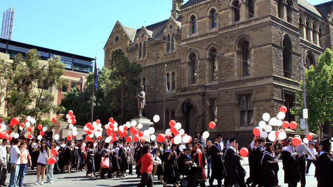 Parade of graduates from RMIT walking down Swanston St in Melbourne on their way to graduation.