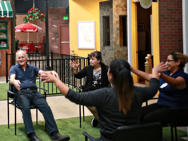 Exercise class in the courtyard at Glenner Town Square facility in Chula Vista, CA on Tuesday, September 11, 2018.  At Glenner Town Square in San Diego there are old-fashioned rotary phones, and typewriters instead of computers. The movie theater plays Jimmy Stewart flicks. The 9,000-square-foot indoor village is surrounded by 11 storefronts, frozen in time. They are meant to represent the era from roughly 1953 to 1961 when the 80-something Alzheimer’s patients who come here were in the prime of their life. Glenner Square is the country’s first memory-care facility built entirely around the idea of reminiscence therapy, a therapy that uses prompts from a person’s past - such as music, movies and photographers - to elicit memories and encourage conversation and activities.(Photo by Sandy Huffaker fr Wall Street Journal)YHEALTH52767 Published Credit: Sandy Huffaker for The Wall Street Journal