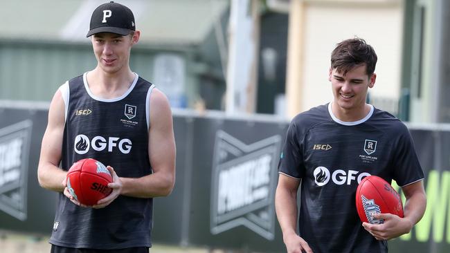 Todd Marshall, with his right shoulder strapped, walks laps with Connor Rozee on Monday. Picture: Sarah Reed