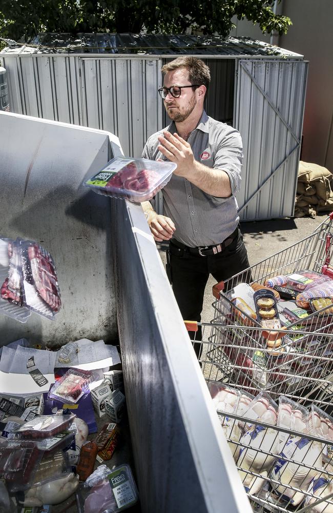 WHAT A WASTE: IGA Hahndorf store manager Tom Ratcliffe throws out shopping trolleys full of food spoiled by this week’s power outage. Picture: MIKE BURTON