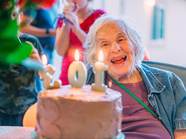 Senior Caucasian Woman Celebrating her 103rd Birthday with a Cake, Surrounded by Family
