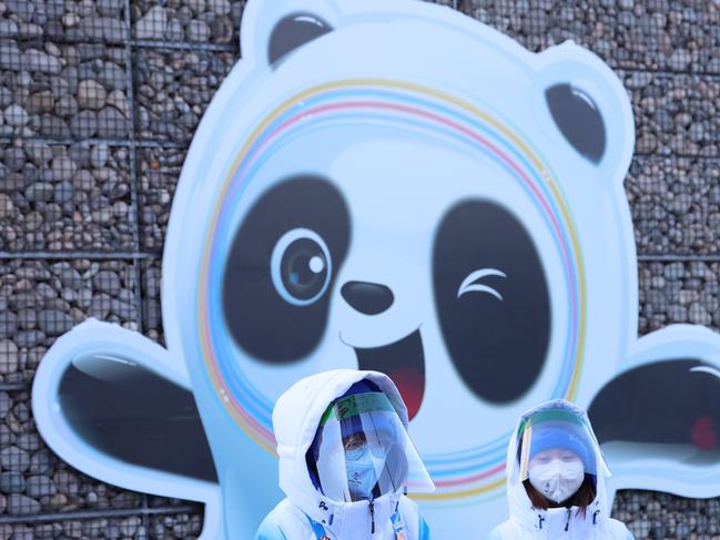 Volunteers in front of a sign of official Winter Olympics mascot Bing Dwen Dwen. Picture: Getty Images