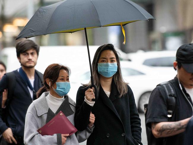 SYDNEY, AUSTRALIA - NCA NewsWire Photos JULY, 27, 2020: Women are seen wearing face masks as they shelter from the rain in Sydney. A severe weather warning is in place for Sydney and the Illawarra, the South Coast and eastern parts of the Snowy Mountains, with the wild weather expected to peak in Sydney this afternoon. Picture: NCA NewsWire / Bianca De Marchi