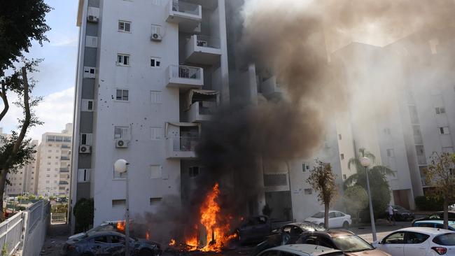 Cars parked outside a residential building catch fire during a rocket attack from the Gaza Strip on the southern Israeli city of Ashkelon. Picture: AFP