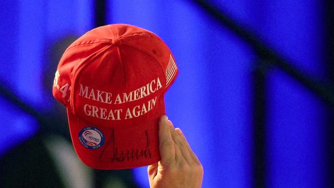 A Trump support holds a signed MAGA hat aloft after he claims the 2024 US election.