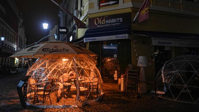 A man sleeps inside a coronavirus protection bubble outside a pub in Bucharest, Romania. Picture: AFP