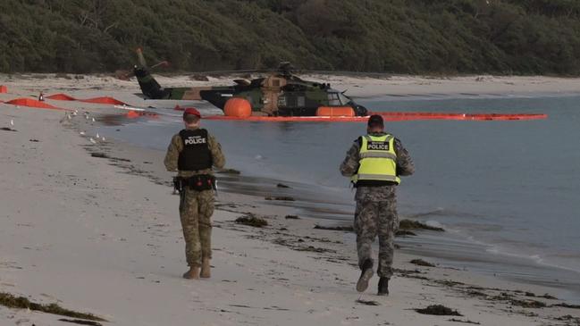 Army personnel are seen on the beach near the MRH-90 Taipan helicopter. Picture: TNV